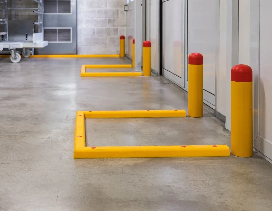 Yellow bollards and a low guard rail protecting a wall and a doorway