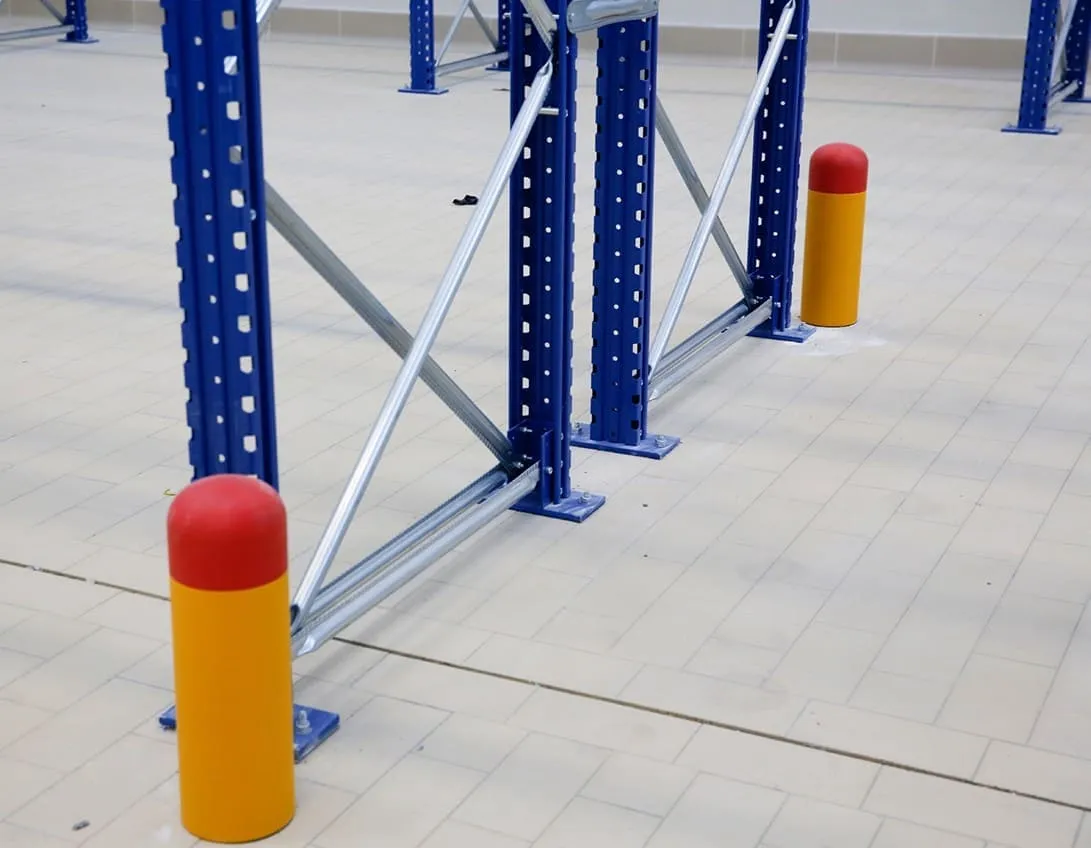 Yellow bollards set in front of the uprights of a pallet racking run