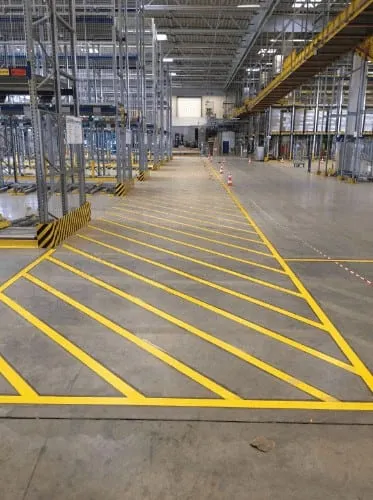 Yellow hatched marking across a warehouse floor beside a row of racking
