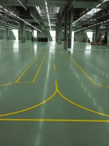 Coated green warehouse floor with yellow traffic lines running into the distance