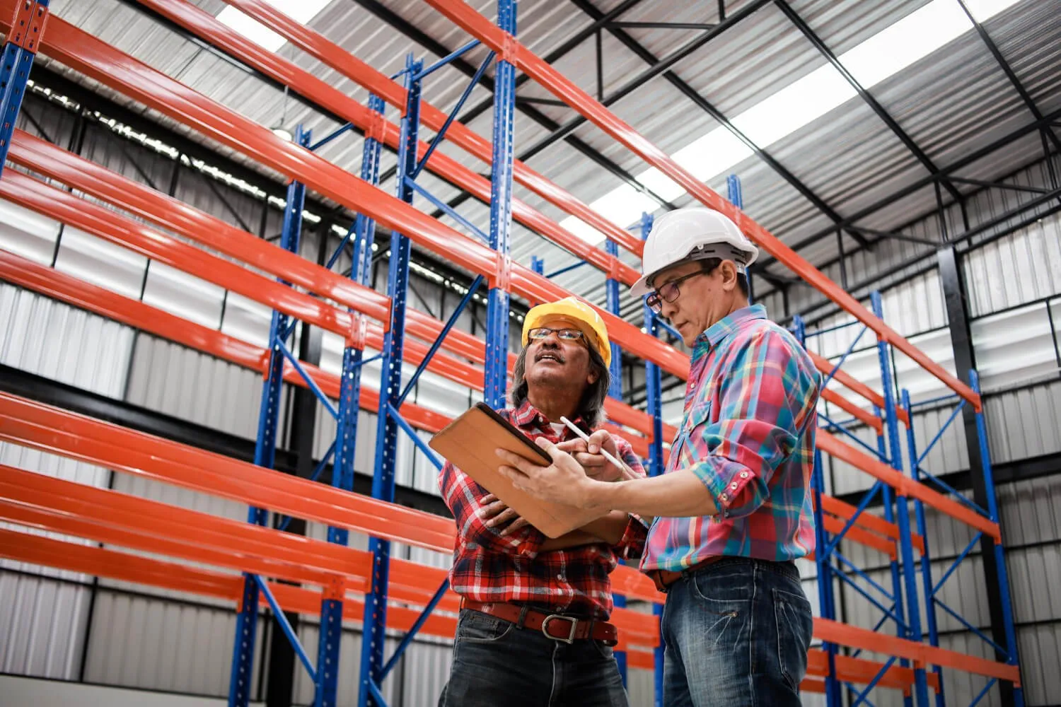 Technician repairing pallet racking inside an operating warehouse