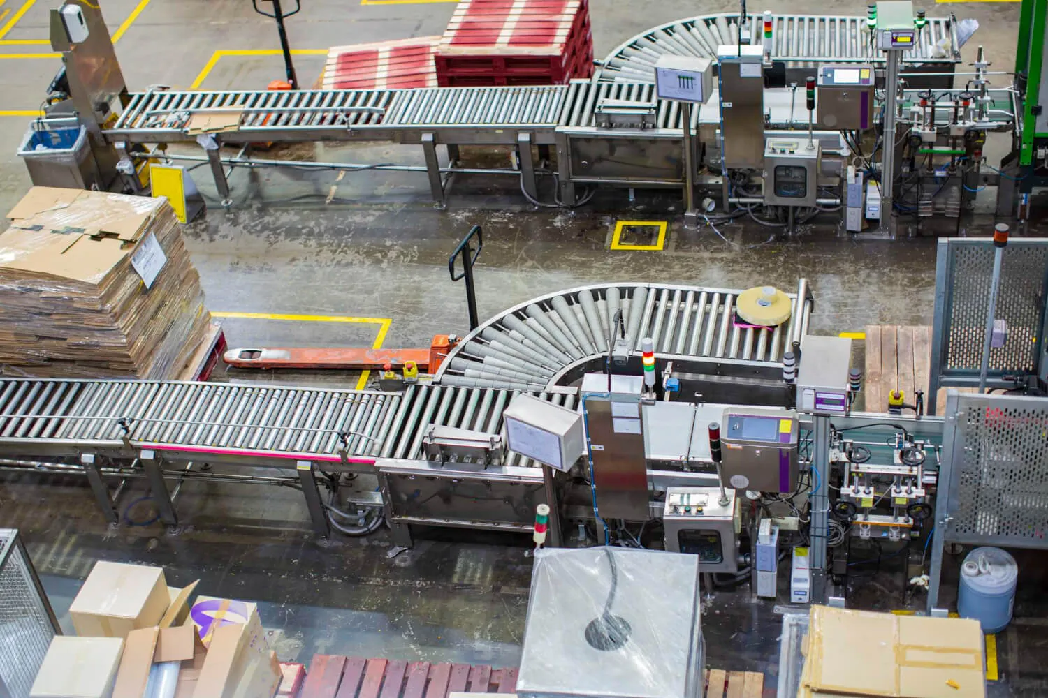Roller conveyors and pallet trucks moving goods across a warehouse floor