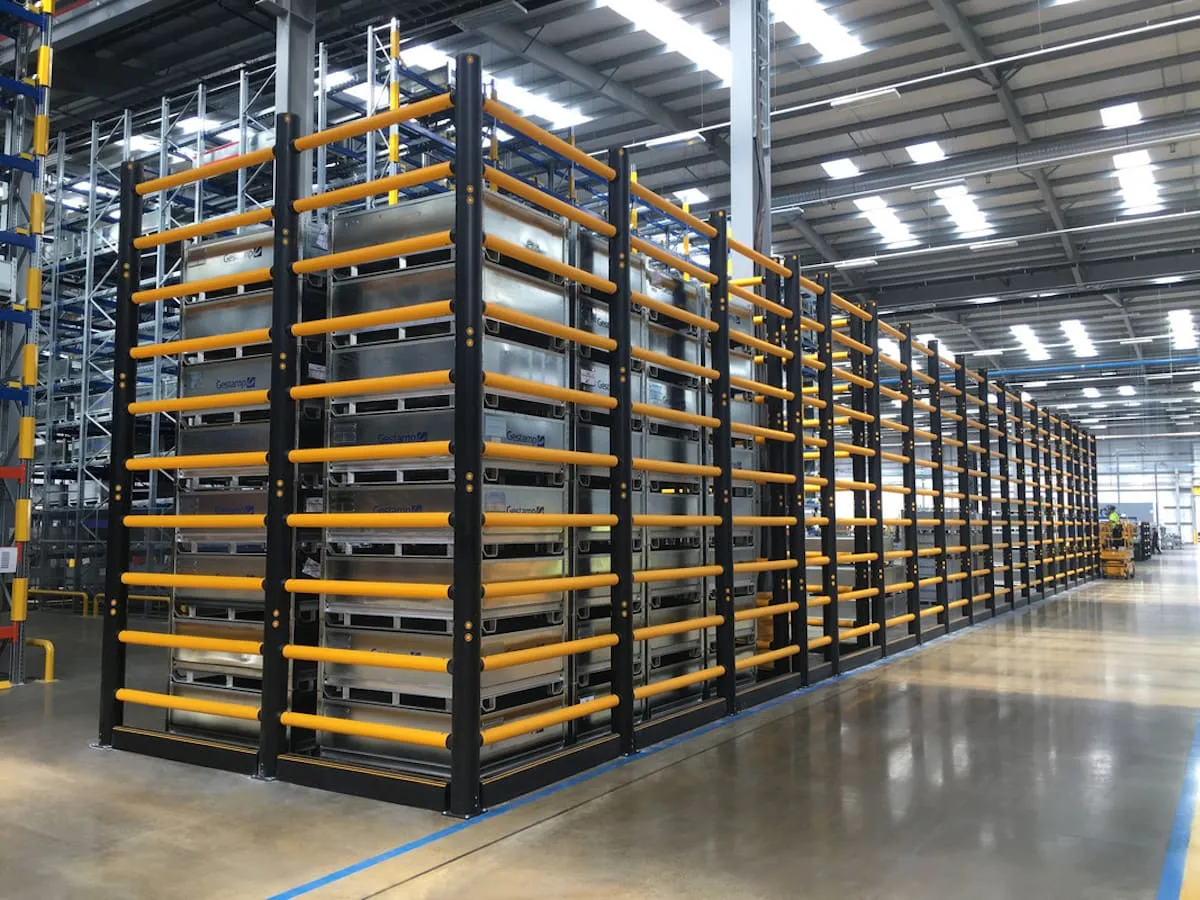 Rows of loaded pallet racking in a warehouse with the main aisle running between them