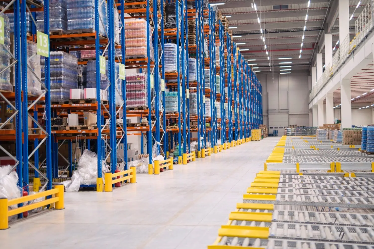 Yellow guard rail running along the base of a racking run in a warehouse aisle