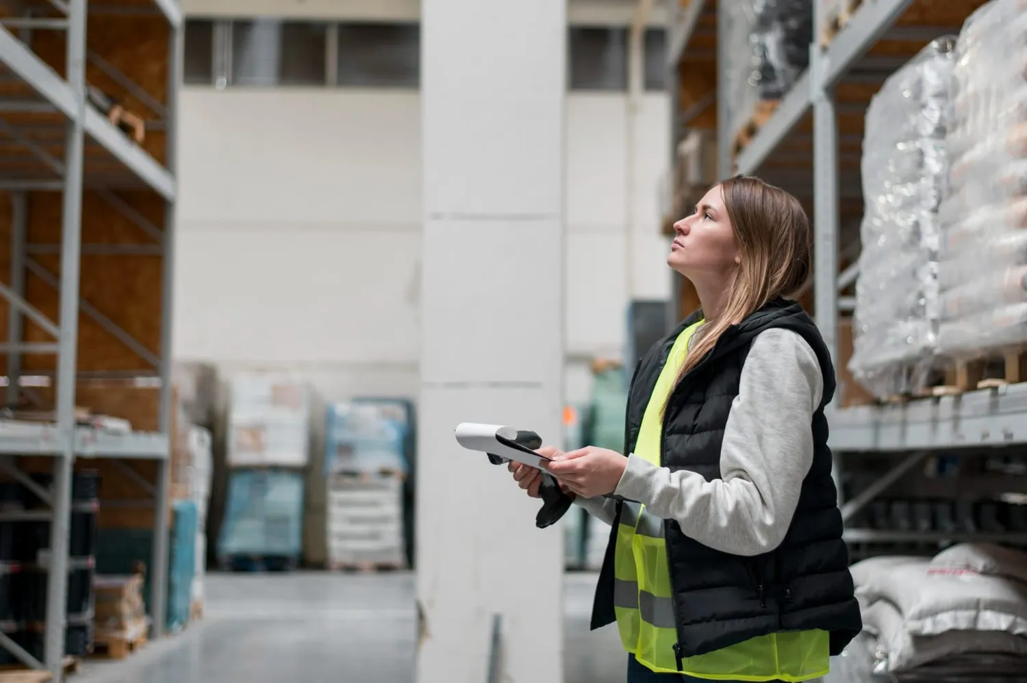Inspector examining a racking upright and recording findings on a clipboard