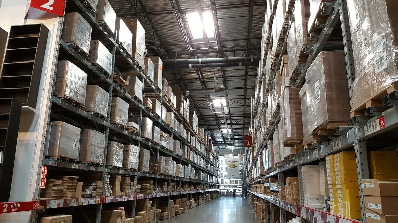 Allée d'entrepôt bordée de rayonnages chargés de cartons et de palettes