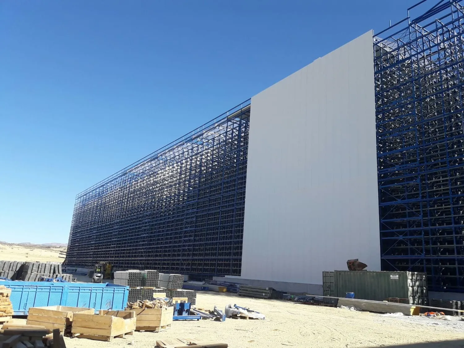 Tall self-supporting clad-rack structure being erected as the warehouse frame