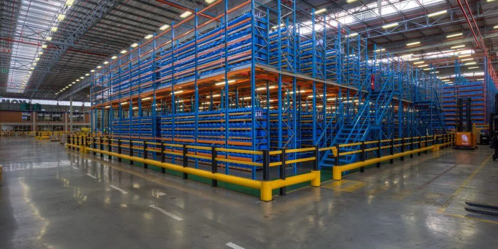 Multi-level mezzanine supported by pallet racking with stairs and guard rails