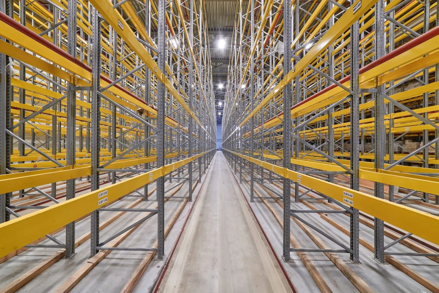 Very narrow aisle between tall racking runs with guide rails fixed along the floor on both sides
