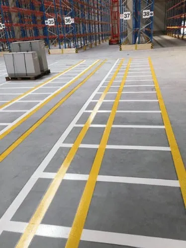 Yellow and white marked lanes on a warehouse floor in front of pallet racking